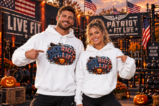 A man and a woman wearing matching white hoodies with a large Halloween 'Patriot Fit Life' graphic on the front, posed in a gym setting with Halloween decorations, pumpkins, gym equipment, and American flags.