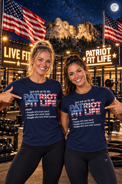 Two women posing in a gym setting, both wearing matching navy blue t-shirts with 'PATRIOT FIT LIFE' printed on the front in red, white, and blue. The background features a large illuminated 'PATRIOT FIT LIFE' sign, American flags, and Mt. Rushmore at night.