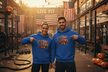A man and a woman standing in a Halloween-themed gym, both wearing matching royal blue hoodies with a colorful Halloween graphic on the chest that reads 'PATRIOT FIT LIFE.'