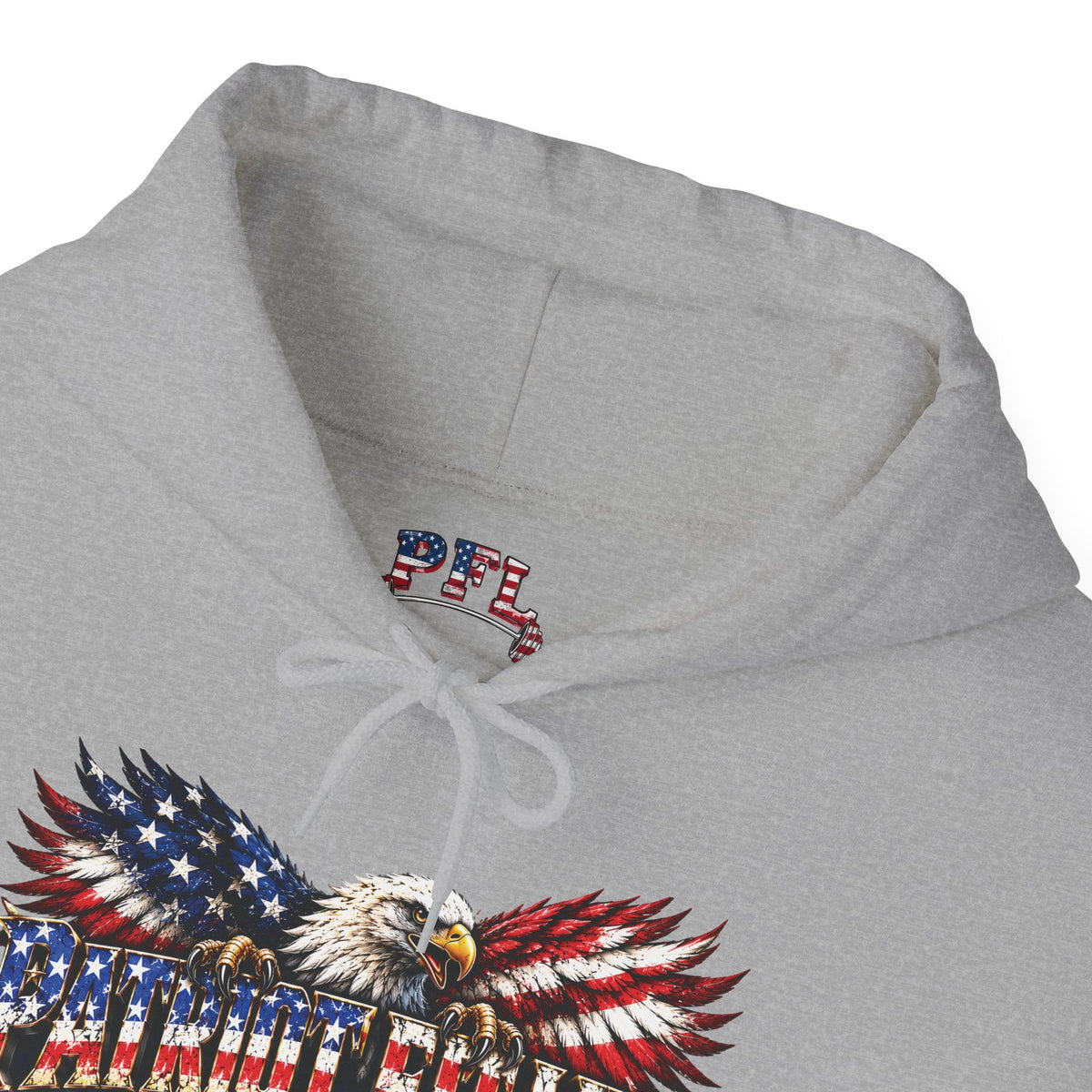 Close-up of a light gray hoodie showing the inside hood lining with a red, white, and blue patriotic PFL (Patriot Fit Life) logo, and part of a large eagle graphic with American flag patterned wings on the front.