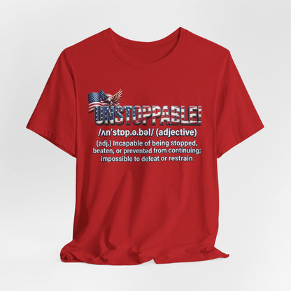 A red short-sleeve crewneck t-shirt with a graphic on the chest featuring the word 'UNSTOPPABLE!' in a distressed American flag pattern, an eagle graphic, and a dictionary definition printed below in white text.