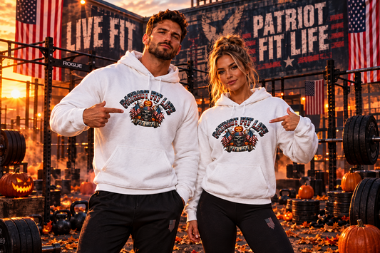 Two fitness athletes posing in a gym setting wearing matching Halloween white graphic hoodies with 'Patriot Fit Life' printed on the chest, pointing at the logos.