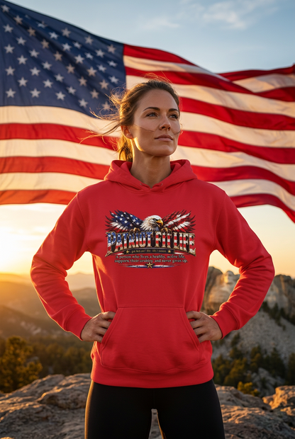 A woman stands on a mountain peak wearing a red hoodie with a PATRIOT FIT LIFE dictionary-style definition, a patriotic eagle with American flag-patterned wings, and an American flag graphic, with a large American flag waving in the background against a colorful sunset sky. 