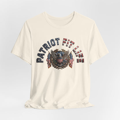 An off-white crewneck t-shirt with a patriotic graphic on the chest reading 'PATRIOT FIT LIFE' in distressed blue, red, and white lettering around an eagle and American flag emblem.