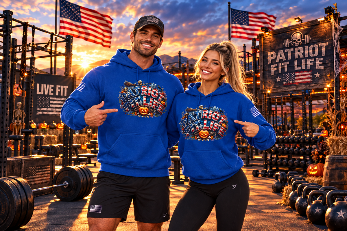 A man and a woman standing together in a gym at sunset, both wearing matching royal blue hoodies with a large Halloween patriotic 'Patriot Fit Life' graphic across the chest. The background features patriotic gym equipment, American flags, and a 'PATRIOT FIT LIFE' and LIVE FIT sign.