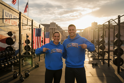 A man and a woman wearing blue hoodies with a PATRIOT American flag pattern text across the front.