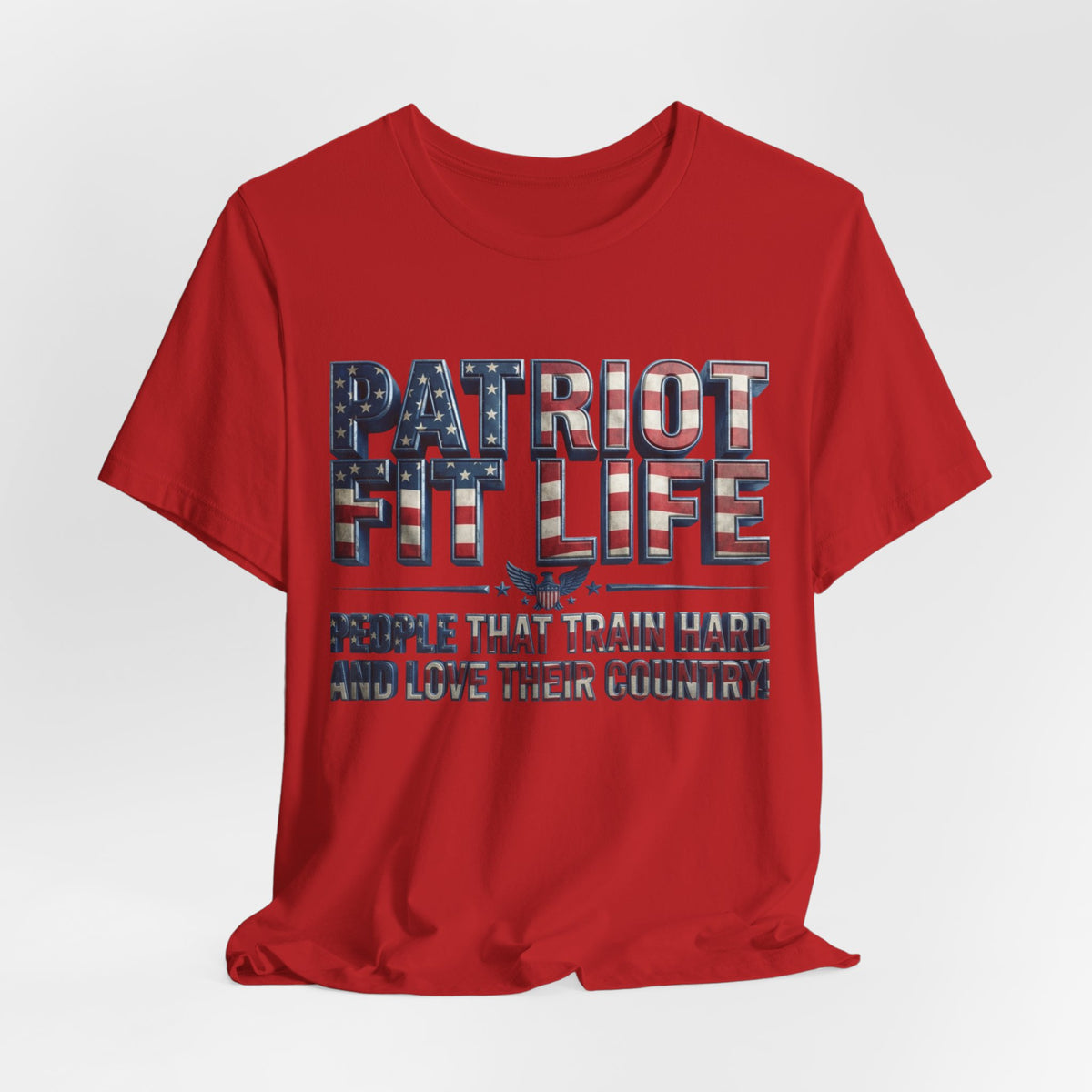 A red short-sleeve crewneck t-shirt with a distressed graphic on the front reading 'PATRIOT FIT LIFE' in an American flag pattern, and 'PEOPLE THAT TRAIN HARD AND LOVE THEIR COUNTRY' below it, shown on a light gray background.
