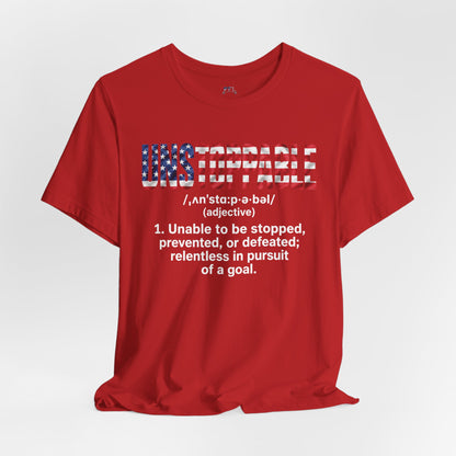 A red short-sleeve crewneck t-shirt with a graphic print on the front. The graphic features the word 'UNSTOPPABLE' in a distressed American flag pattern, with its dictionary definition printed below in white text.